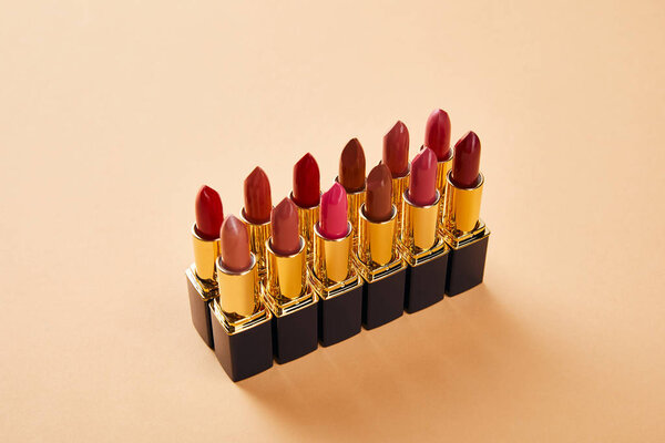 various shades of lipstick in tubes on beige 