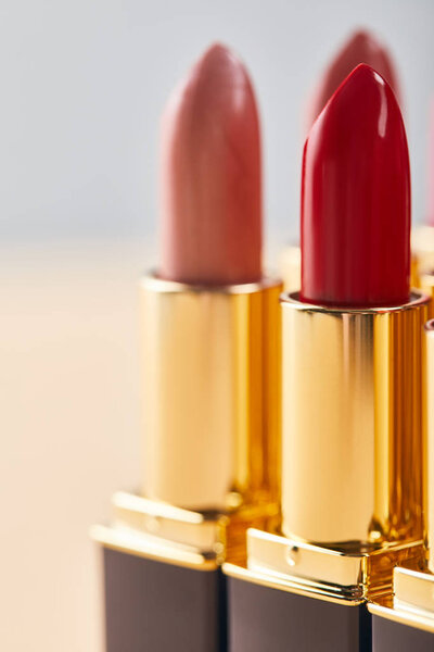 close up of various red lipstick in tubes on beige 