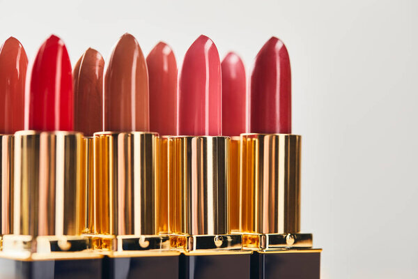selective focus of various red shades of lipsticks isolated on grey 