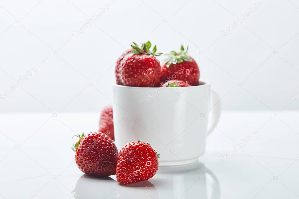 ripe sweet strawberries in cup on white background