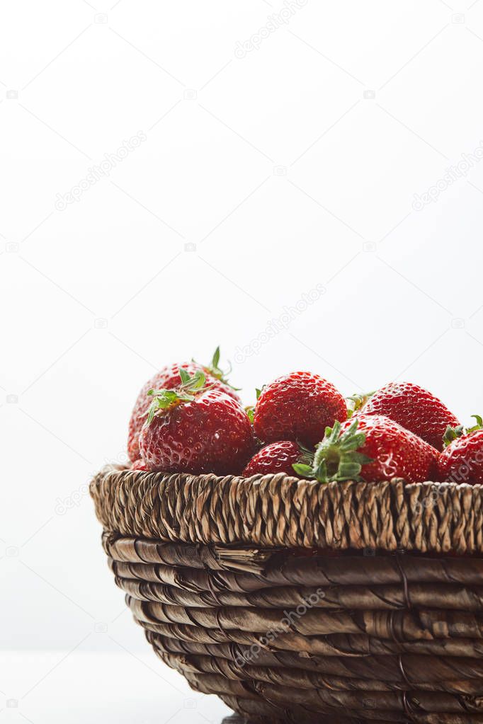 red organic strawberries in wicker basket isolated on white