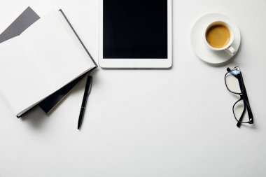 beyaz yüzeyli kalemli dijital tablet, kahve, gözlük ve dizüstü bilgisayarların üst görünümü