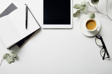 beyaz yüzeyüzerinde kalem ile bitkiler, dijital tablet, kahve, gözlük ve dizüstü bilgisayarlar üst görünümü