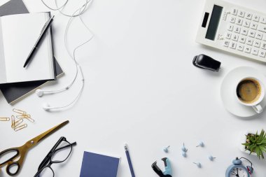 beyaz yüzeyde bitki, gözlük, kahve, kulaklık ve ofis malzemeleri üst görünümü