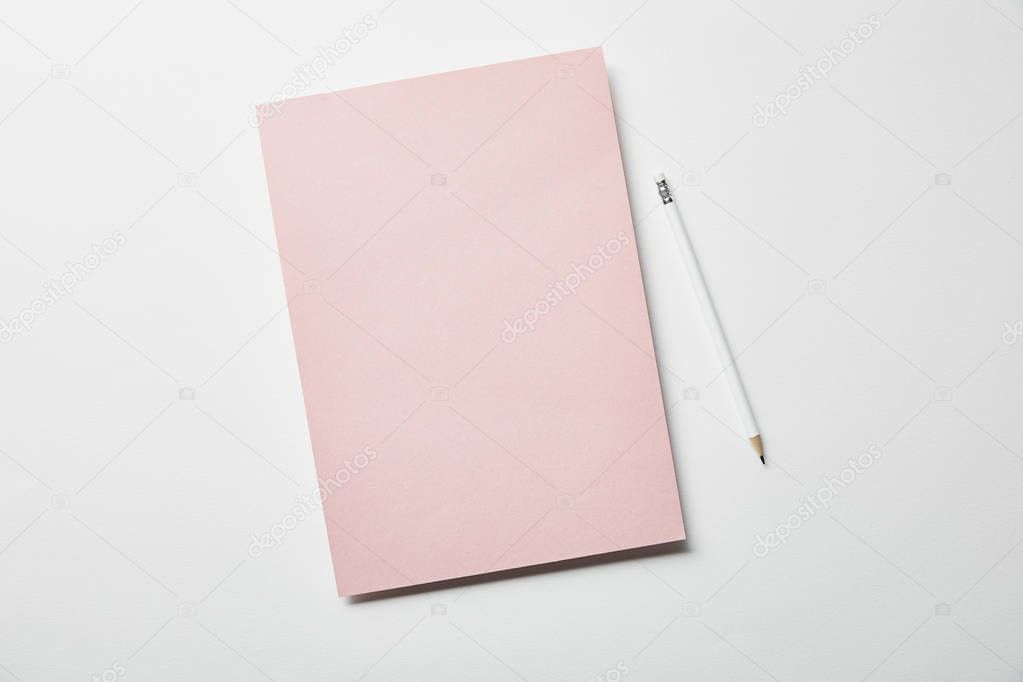 top view of pink paper and pencil on white surface