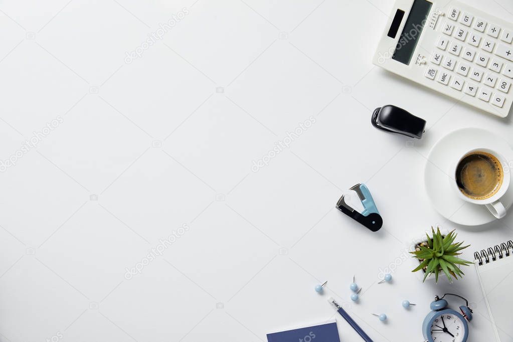 top view of plant, coffee and office supplies on white surface