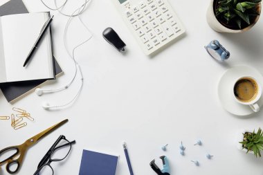 beyaz yüzeyüzerinde bitkiler, gözlükler, kulaklıklar ve ofis malzemeleri üst görünümü