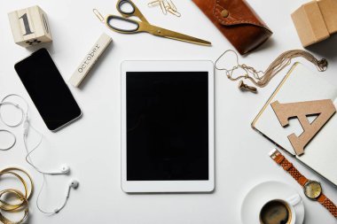 beyaz yüzeyüzerinde takı ile dijital tablet, akıllı telefon, not defteri, kasa, kulaklık, bitki, ofis malzemeleri ve kahve üst görünümü