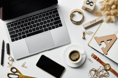 kırtasiye, bitkiler, takı, not defteri ve kahve ile beyaz yüzeyüzerinde dizüstü bilgisayar ve akıllı telefon üst görünümü