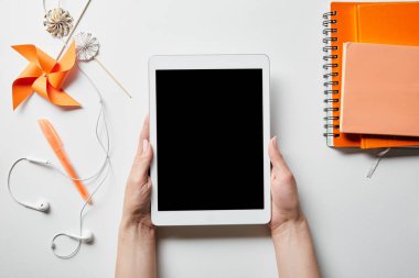 turuncu dizüstü bilgisayarlar, dekorasyon nesneleri ve kulaklıklar beyaz yüzeyüzerinde yakın dijital tablet tutan kadın kırpılmış görünümü