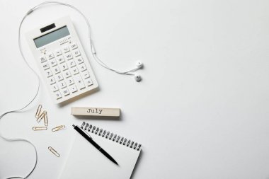 kırtasiye, hesap makinesi, kulaklık ve beyaz yüzeyli kalem ile dizüstü üst görünüm