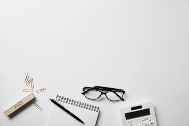 beyaz yüzeyüzerinde gözlük, kalem, hesap makinesi ve kırtasiye ile dizüstü üst görünümü