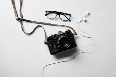 top view of earphones, glasses and photo camera on white surface clipart