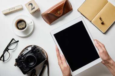 fotoğraf makinesi, kahve, kasa, not defteri, beyaz yüzeyüzerinde sayılar ve harfler ile blok yakınında dijital tablet tutan kadın kırpılmış görünümü