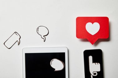 kağıt düşünce ve konuşma kabarcıkları, kağıt kalp, beyaz yüzey üzerinde işaret kartı ile dijital tablet ve akıllı telefon