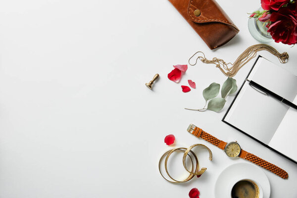 top view of notepad, pen, case, plants and coffee on white surface