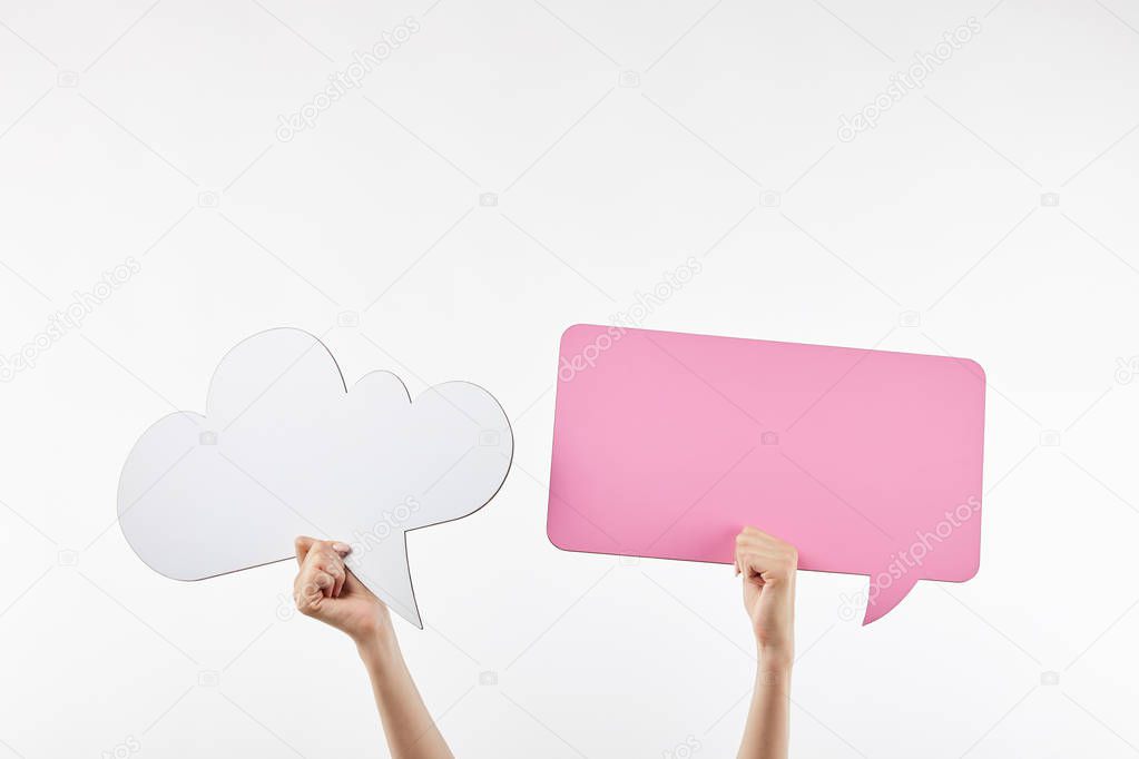 cropped view of woman with pink thought and speech bubbles in hands isolated on white