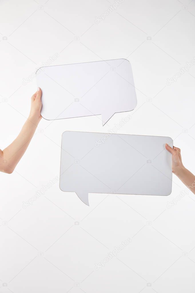 cropped view of two women with speech bubbles in hands isolated on white