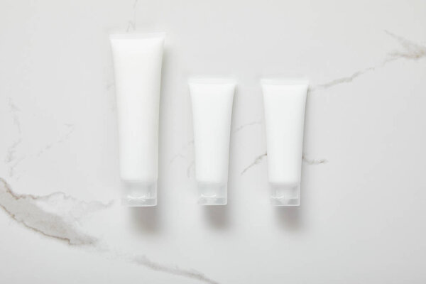 верхний вид косметических кремовых трубок на белой поверхности
