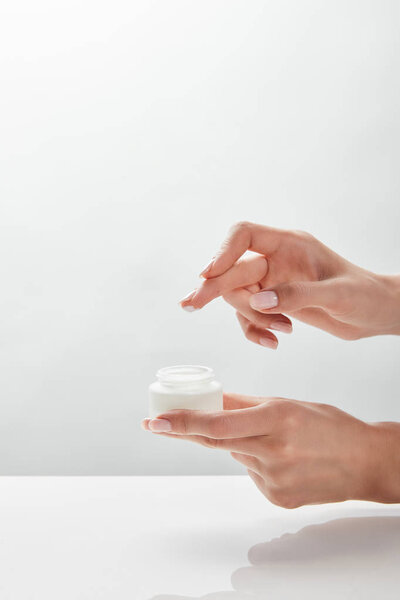 cropped view of woman holding jar with cream in hands