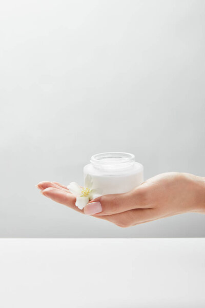 cropped view of woman holding jar with cream on palm hand