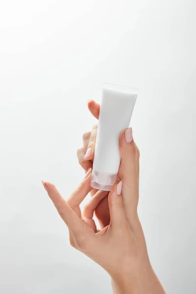 白で隔離された手に化粧品クリームチューブを保持している女性のトリミングビュー — ストック写真