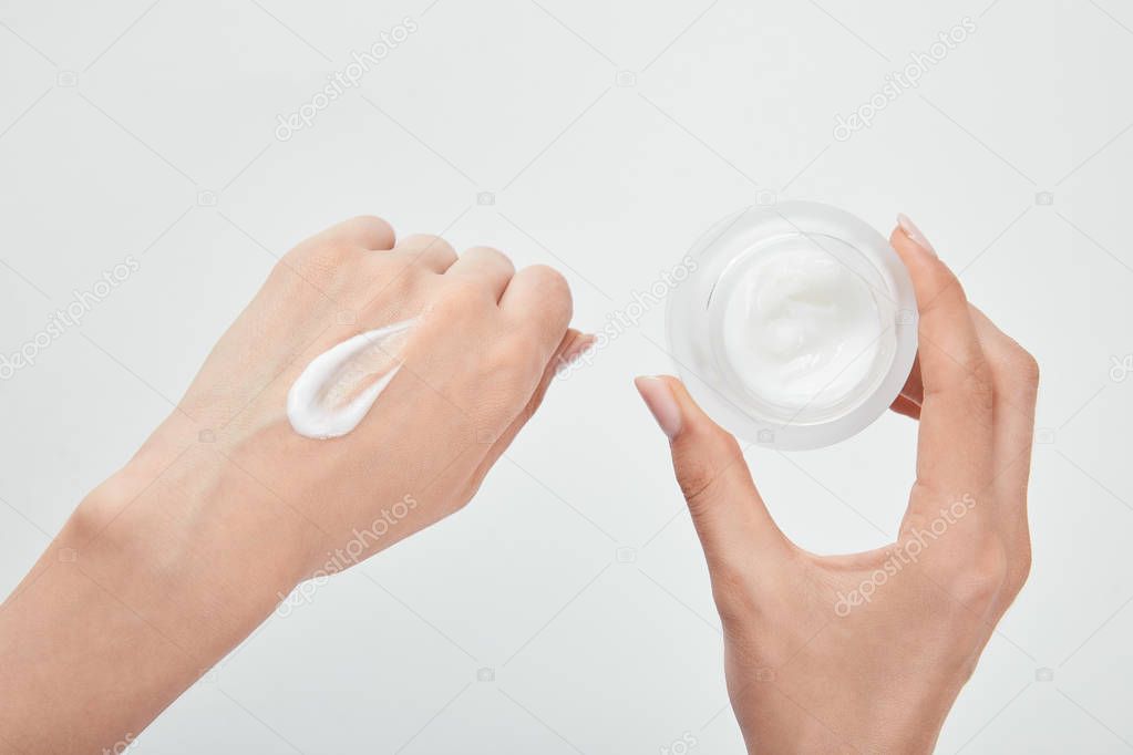 cropped view of woman with cream in hand and skin isolated on white