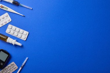 blister paketleri, burun spreyi, termometre, glucometer ve şırıngalar mavi izole üst görünümü