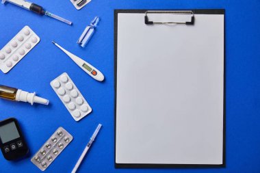 mavi izole çeşitli tıbbi malzemeler tarafından yuvarlak boş kağıt ile klasörün üst görünümü