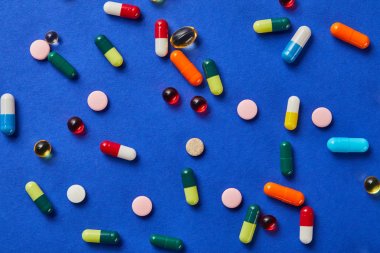 top view of different medical pills on blue background clipart