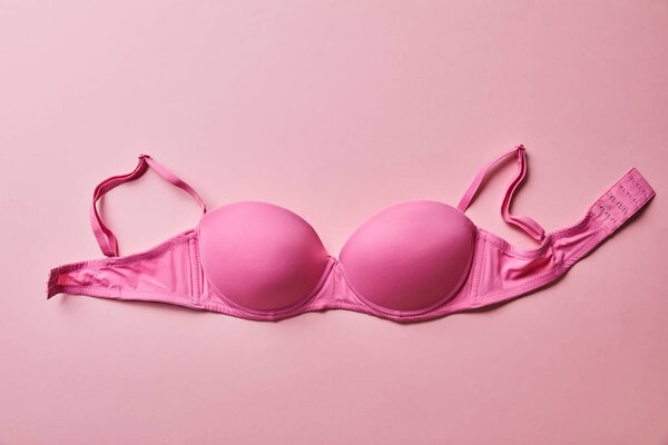 top view of pink brassiere on light pink background, breast cancer concept