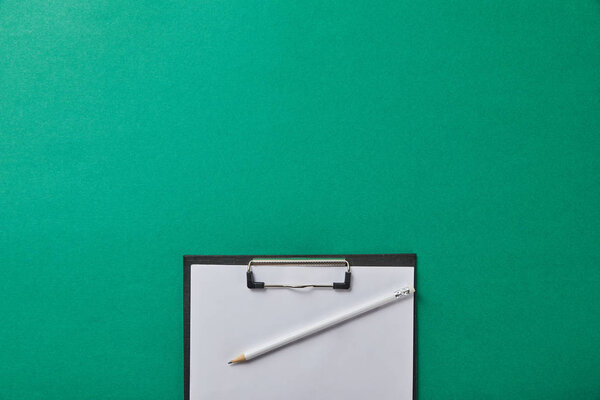 верхний вид карандаша на папке с пустой бумагой, изолированной на зеленом
