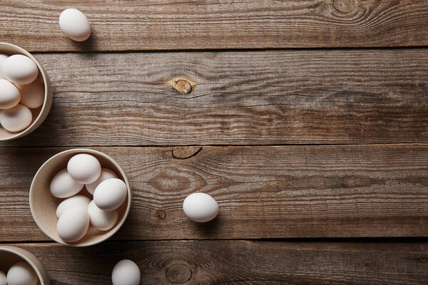  top view of chicken eggs in bowls on wooden table
