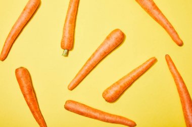top view of fresh carrots on yellow background clipart