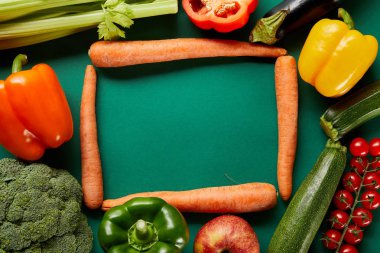 frame of green fresh vegetables and carrots on green background clipart