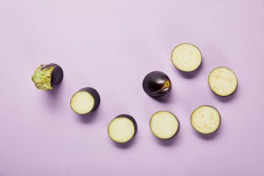 top view of ripe sliced eggplant on violet background with copy space clipart
