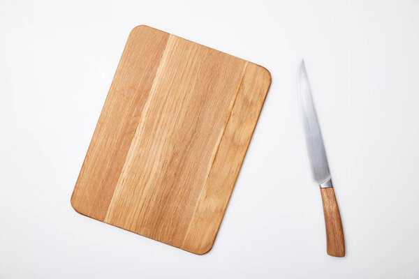 top view of empty wooden chopping board and knife on white background