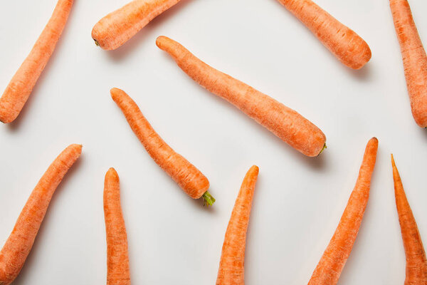 top view of fresh carrots scattered on white background