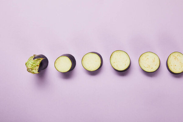 top view of ripe sliced eggplant on violet background with copy space