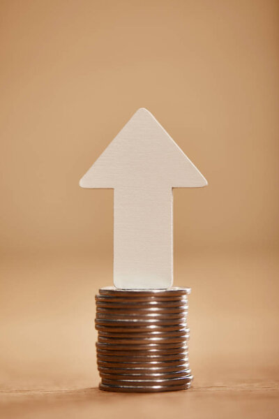 stack of coins with white arrow upwards, financial growth concept