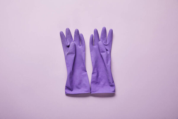 top view of bright and colorful rubber gloves on purple background 