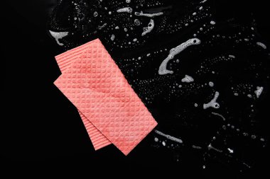 siyah arka plan üzerinde köpük ile pembe bez üst görünümü 