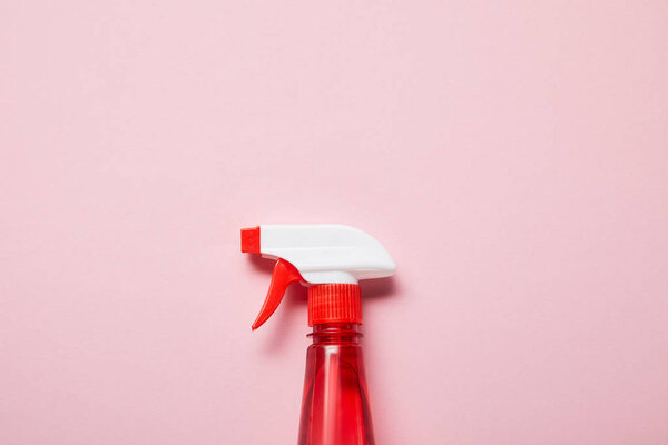 top view of red bottle with spray on pink background 