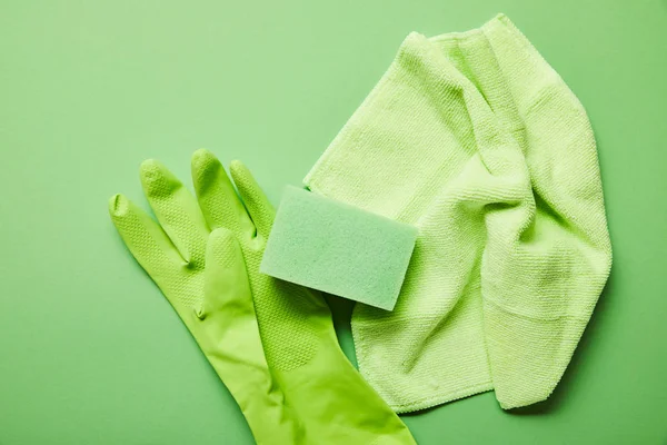 五颜六色的抹布 橡胶手套和海绵在绿色背景的顶视图 — 图库照片