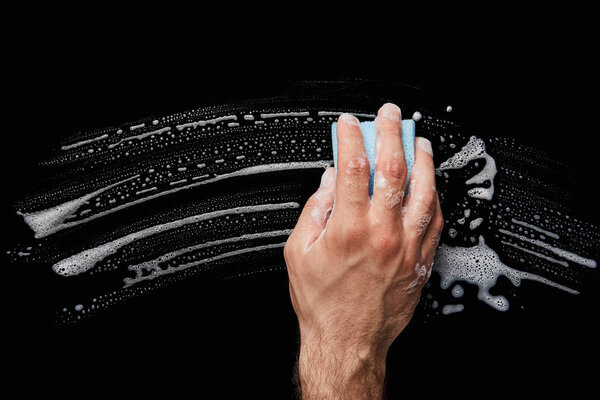 cropped view of man cleaning with blue sponge on black background 