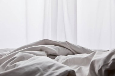 perde yakınında yatakta buruşuk beyaz pamuklu battaniye