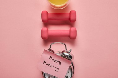 gümüş çalar saat, pembe halter ve pembe arka plan üzerinde portakal suyu üzerinde mutlu sabah yazı ile düz yatıyordu