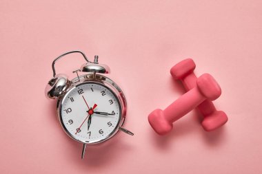 pembe arka plan üzerinde gümüş çalar saat ve pembe halter üst görünümü