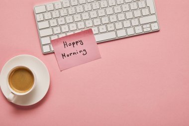 bilgisayar klavyesi ve pembe arka plan üzerinde kahve yakın mutlu sabah harfleri ile pembe yapışkan not üst görünümü