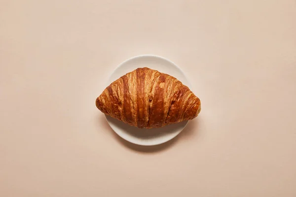Vue Dessus Croissant Savoureux Sur Plaque Blanche Sur Fond Beige — Photo
